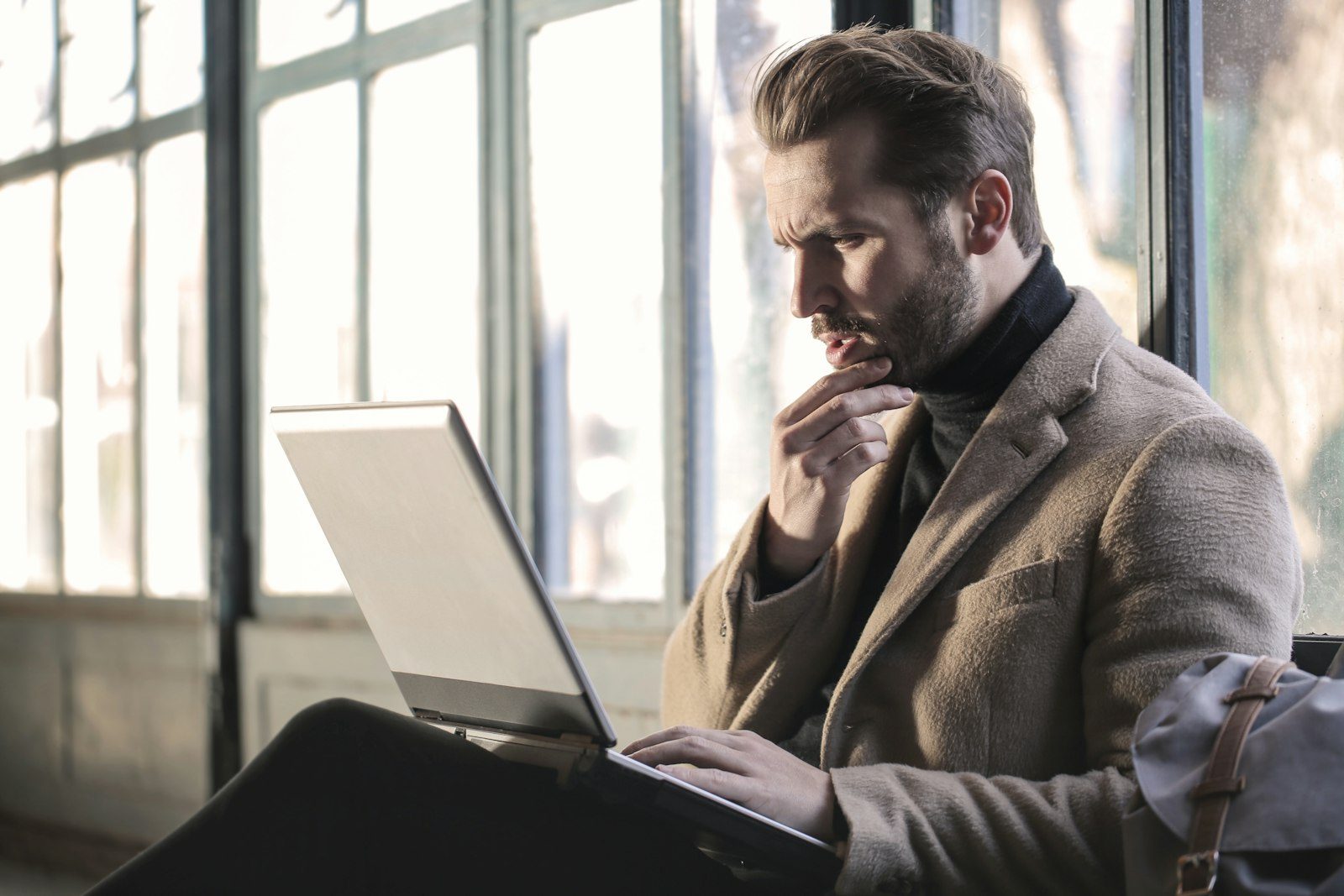 A business owner working at a laptop by a bright office window